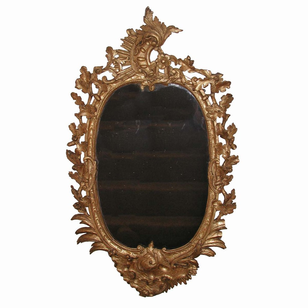 An English carved and gilded oval mirror with acanthus leaf and floral motifs. view 1
