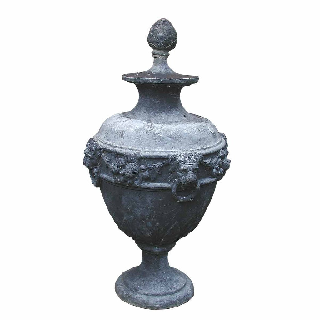 An antique lead urn with lid and adorned with lions' heads and flowers. view 1