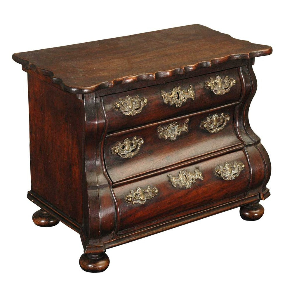 A 18th century mahogany bombe-shaped model chest of drawers on bun feet. view 1