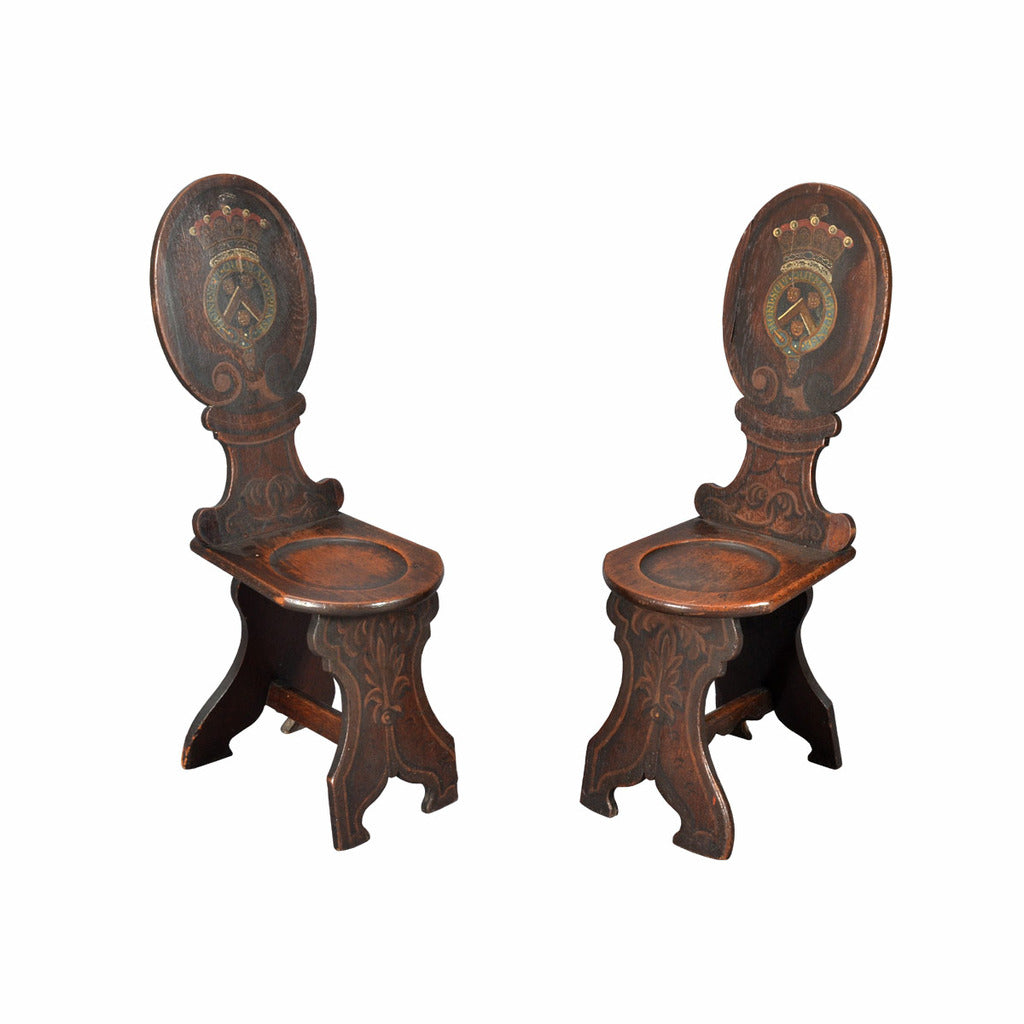 A pair of oak hall chairs; the oval backs painted with an armorial. view 1
